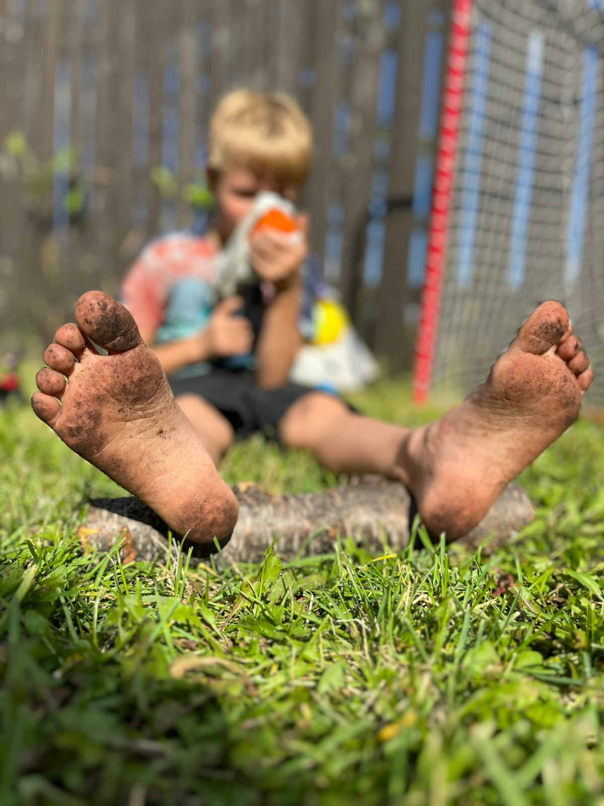 [PT-PLACEHOLDER] Niño sentado en la hierba con los pies arriba
